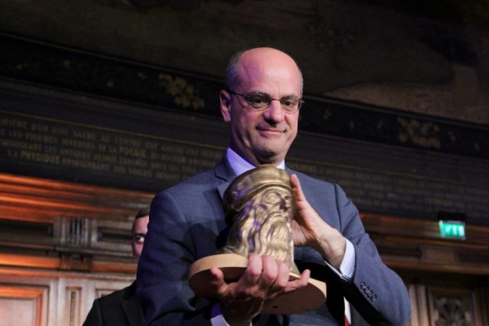 Le ministre Jean-Michel Blanquer montre au public du grand amphithéâtre en Sorbonne le buste en bronze de Léonard De Vinci que les lauréats de la spécialité fonderie du Concours général 2019 lui ont remis sur scène.